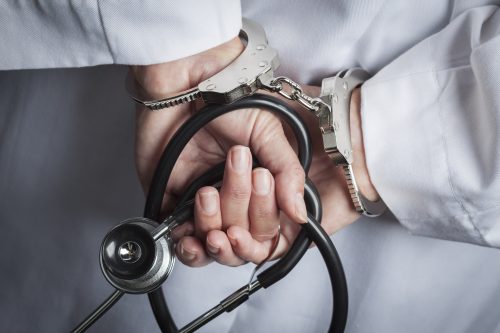 handcuffed healthcare provider because of doing one of the common types of healthcare fraud sample photo